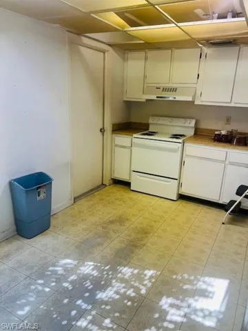 Kitchen featuring white electric stove and white cabinetry