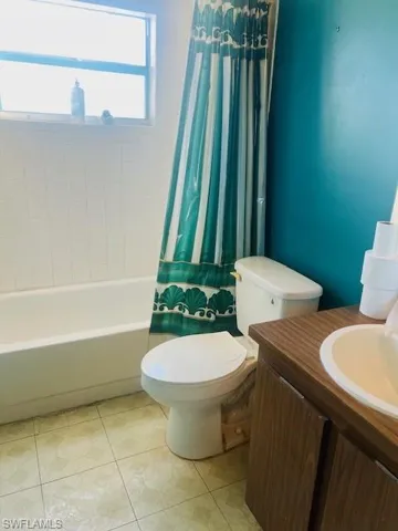 Full bathroom featuring shower / bath combination with curtain, vanity, tile patterned floors, and toilet