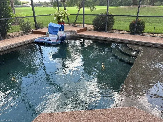 View of swimming pool with a lawn and glass enclosure