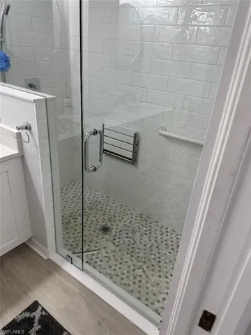Bathroom featuring hardwood / wood-style floors, a shower with shower door, and vanity