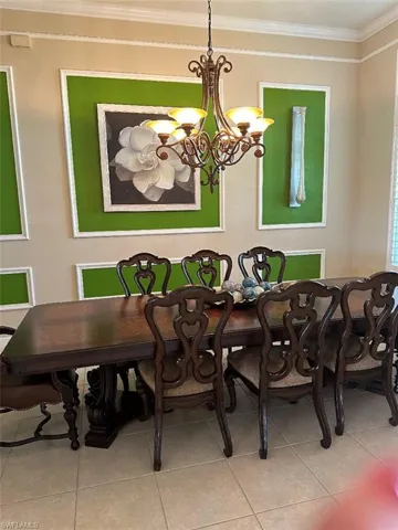 Dining space with crown molding, a chandelier, and tile patterned floors
