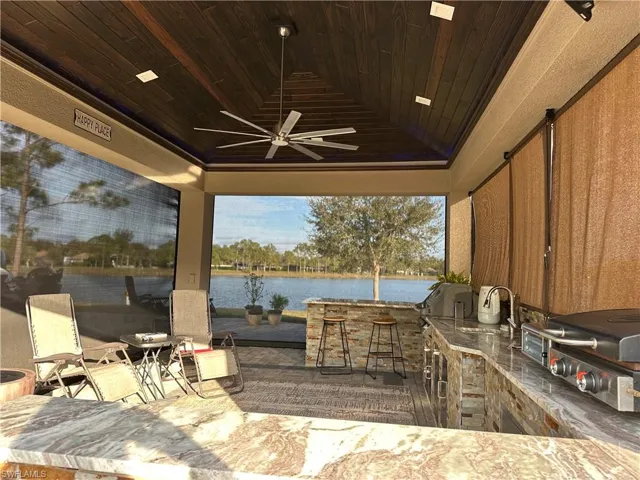 View of patio with ceiling fan, area for grilling, a water view, and an outdoor wet bar