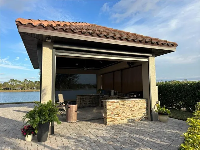 View of patio / terrace featuring ceiling fan, a water view, an outdoor bar, and an outdoor kitchen