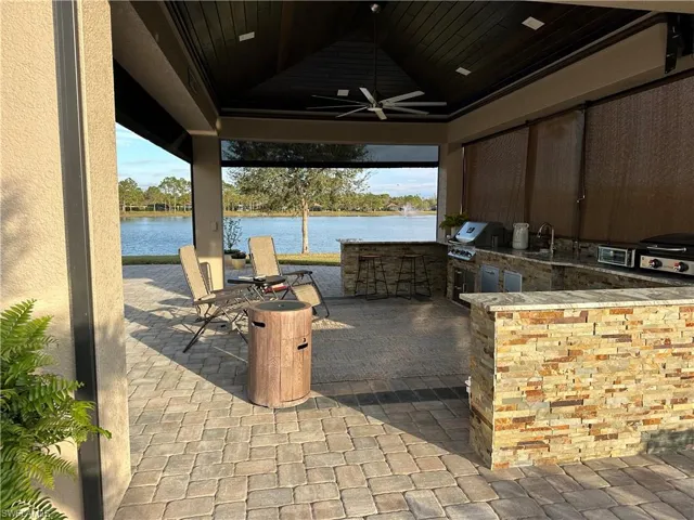 View of patio featuring an outdoor kitchen, a water view, an outdoor wet bar, ceiling fan, and area for grilling