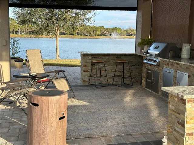 View of patio with exterior kitchen, a water view, an outdoor bar, and grilling area
