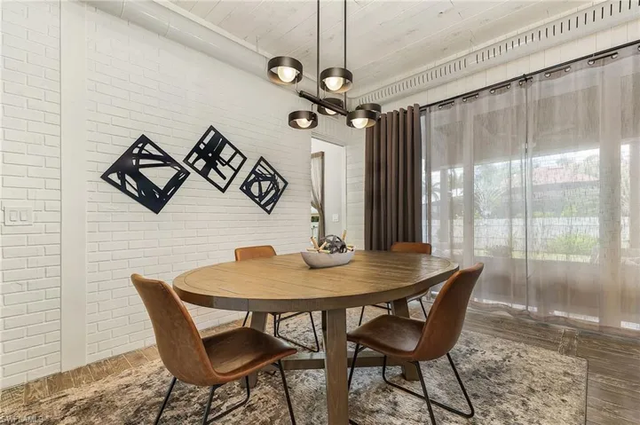 Dining space with an inviting chandelier, brick wall, wooden ceiling, and wood-type flooring