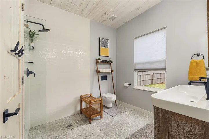 Bathroom featuring vanity, tiled shower, wooden ceiling, and toilet
