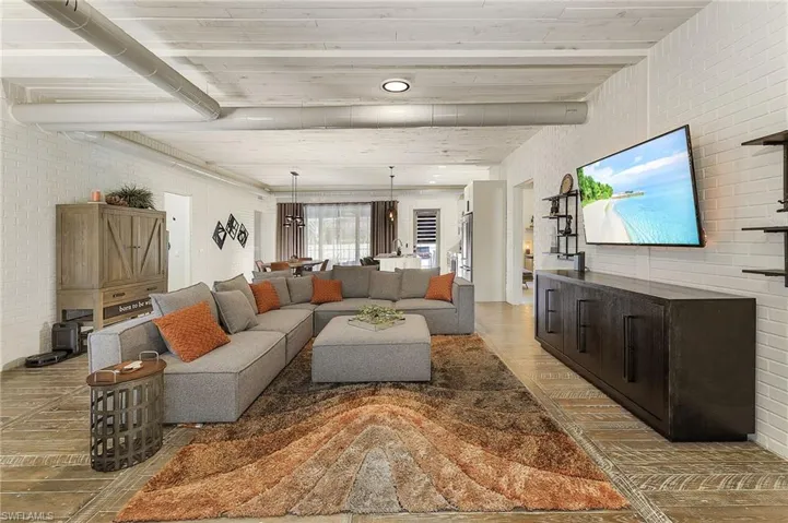 Living room featuring brick wall, beamed ceiling, and hardwood / wood-style flooring