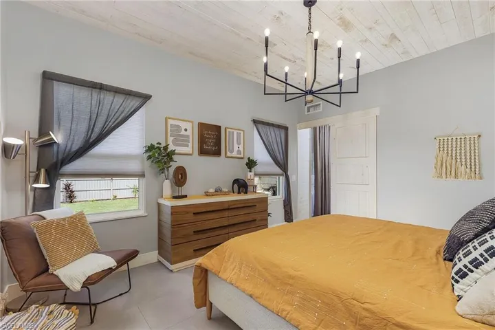 Tiled bedroom featuring wood ceiling and a chandelier
