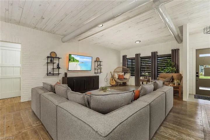 Living room featuring brick wall and dark hardwood / wood-style floors