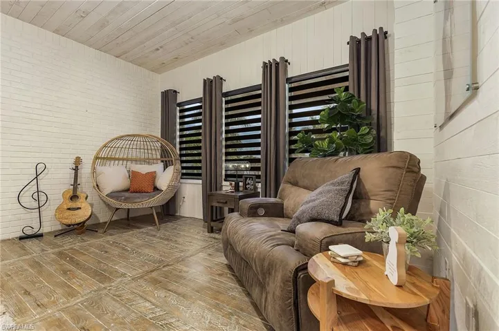 Living area with brick wall, hardwood / wood-style flooring, and wood ceiling