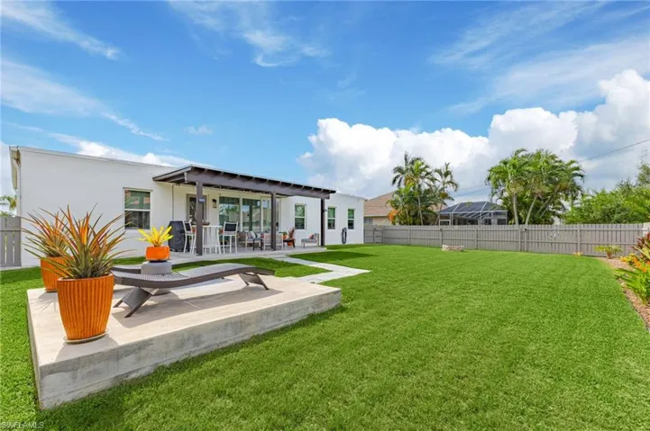 Back of property featuring a lanai, a patio area, and a lawn