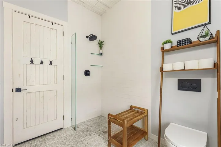 Bathroom with toilet, a tile shower, and tile patterned flooring