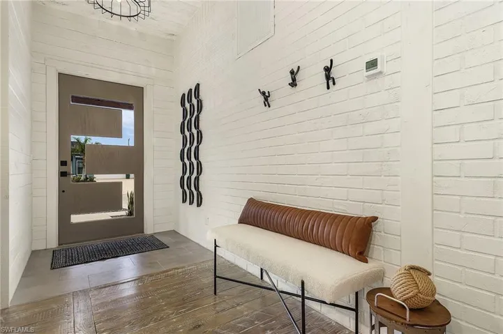 Entrance foyer featuring brick wall and dark wood-type flooring