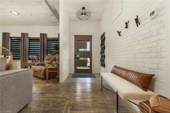 Entrance foyer featuring brick wall and dark wood-type flooring