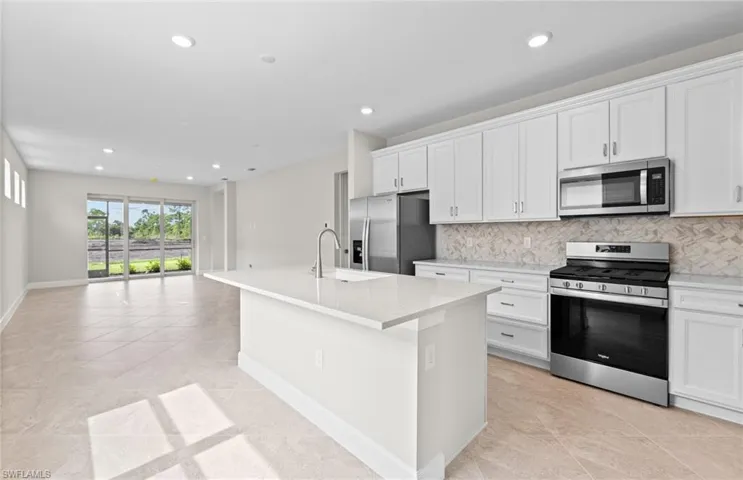 Kitchen featuring white cabinets, sink, a center island with sink, appliances with stainless steel finishes, and decorative backsplash