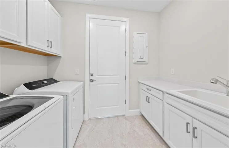 Laundry area featuring washing machine and dryer, sink, and cabinets