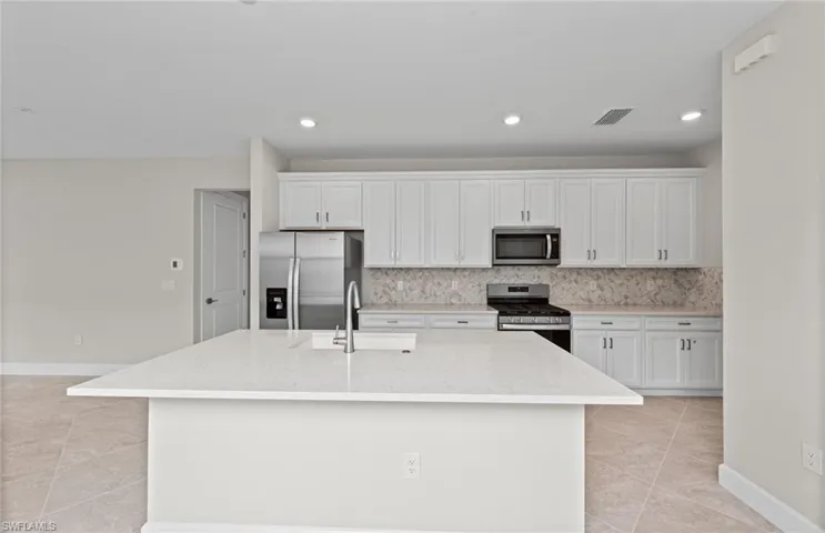 Kitchen featuring an island with sink, white cabinetry, sink, and stainless steel appliances