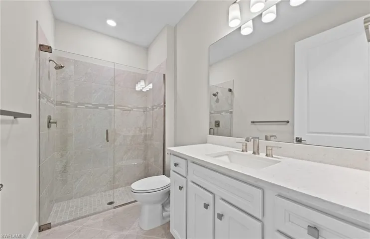 Bathroom with tile patterned flooring, an enclosed shower, vanity, and toilet