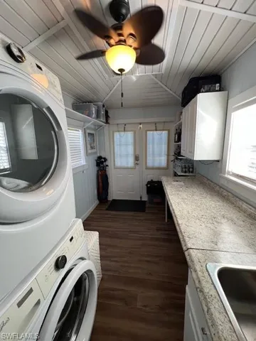 Washroom featuring stacked washer and dryer, sink, wooden ceiling, dark hardwood / wood-style flooring, and ceiling fan