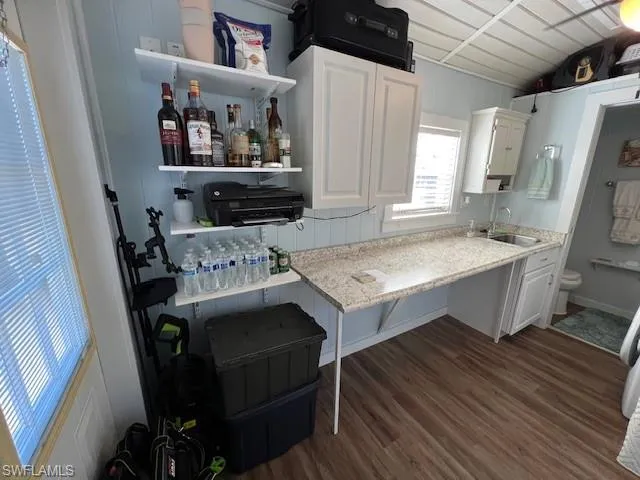Kitchen with sink, dark wood-type flooring, light stone countertops, and white cabinets