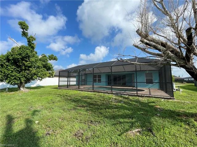 Rear view of property with a sunroom, glass enclosure, and an outdoor pool