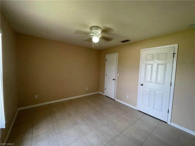 Unfurnished bedroom with ceiling fan and light tile patterned floors