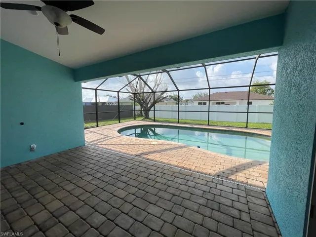 View of swimming pool with a sunroom, a patio area, glass enclosure, ceiling fan, and a residential view