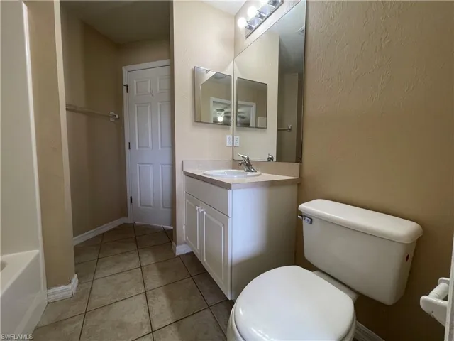 Full bath with vanity, light tile patterned floors, a tub to relax in, and a textured wall