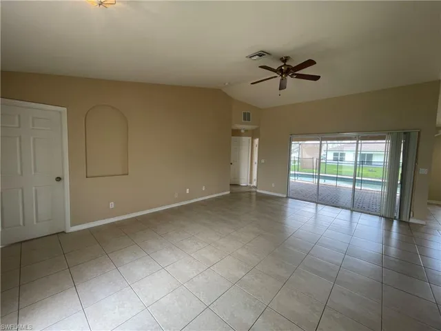 Unfurnished room with vaulted ceiling, light tile patterned floors, and a ceiling fan