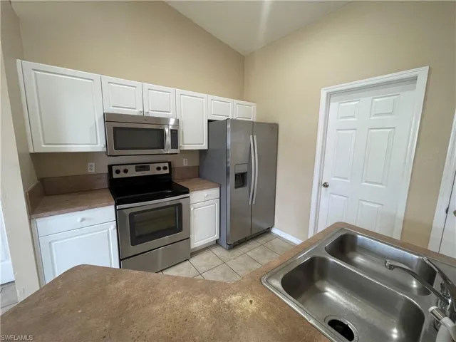 Kitchen featuring appliances with stainless steel finishes, white cabinetry, and light tile patterned floors
