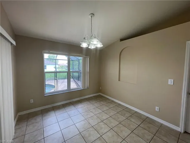 Empty room featuring light tile patterned floors, a chandelier, and vaulted ceiling