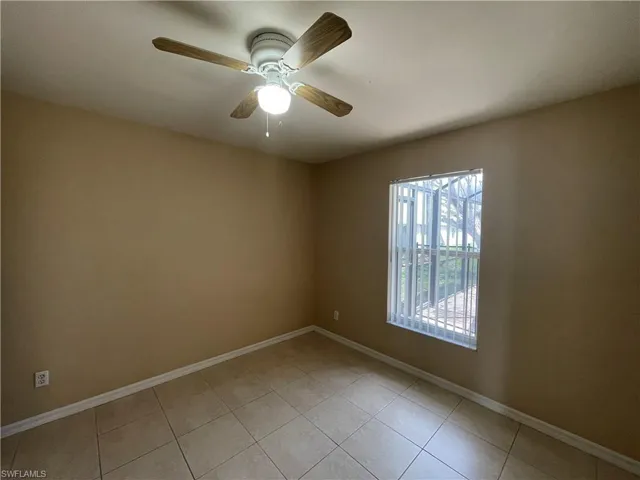 Empty room with light tile patterned floors and a ceiling fan