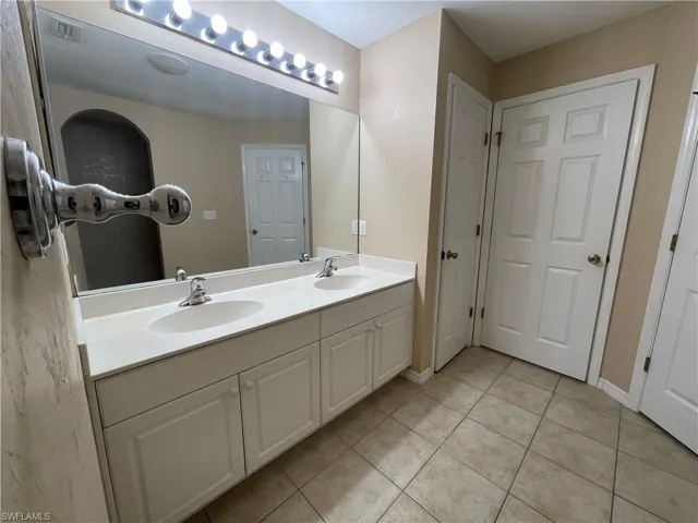 Bathroom with light tile patterned floors and double vanity