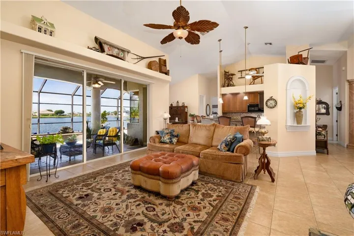 Living room featuring a water view, high vaulted ceiling, light tile patterned floors, and ceiling fan