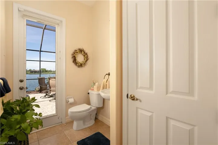 Pool/ Guest Bathroom with toilet, a water view, tile patterned flooring, and plenty of natural light