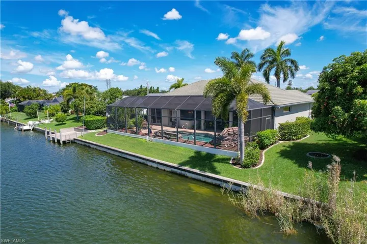 Rear view of house featuring a water view, a yard, glass enclosure, and a pool