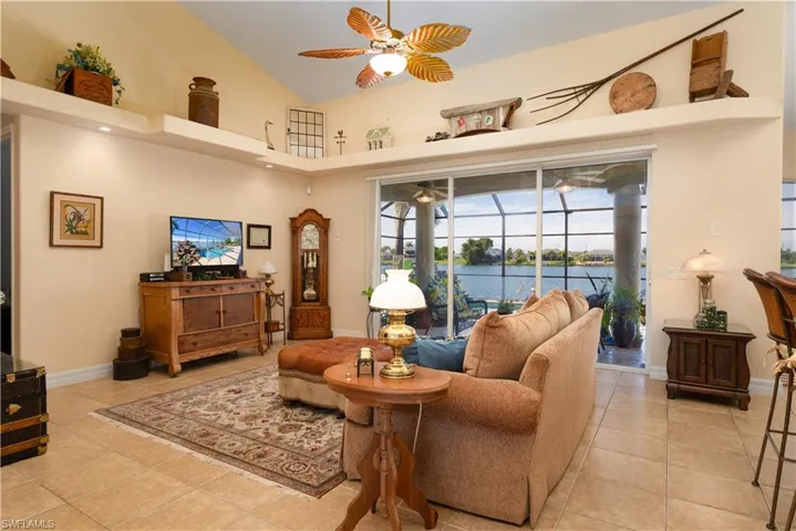 Tiled living room featuring a water view, ceiling fan, and high vaulted ceiling