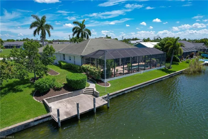 Rear view of house featuring a water view, a lawn, and glass enclosure