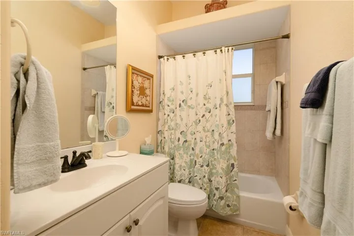 Full bathroom with tile patterned floors, vanity, shower / bathtub combination with curtain, and toilet