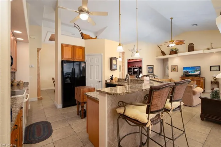 Kitchen featuring hanging light fixtures, black fridge, light tile patterned floors, and ceiling fan