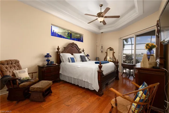 Bedroom featuring ceiling fan, hardwood / wood-style flooring, ornamental molding, and a tray ceiling