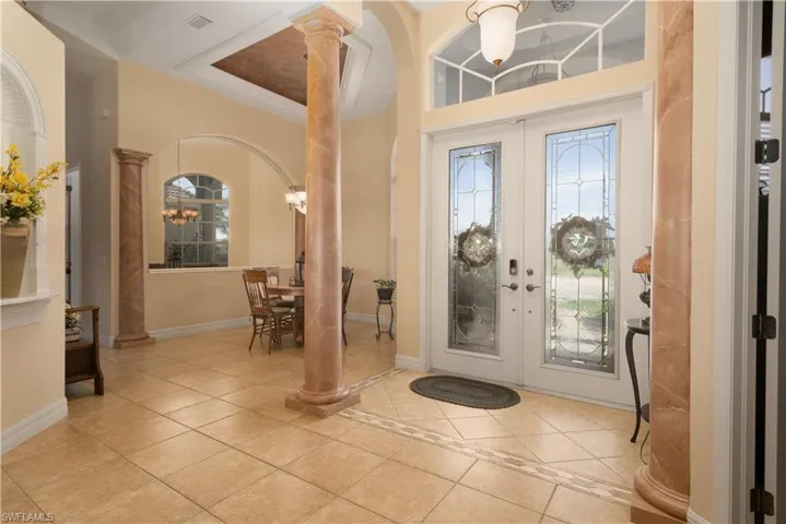 Tiled foyer with decorative columns and french doors