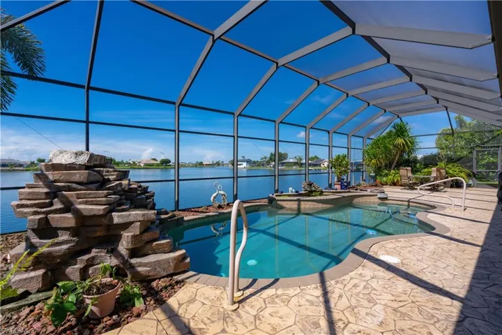 View of swimming pool with a patio area, a water view, a jacuzzi, and glass enclosure