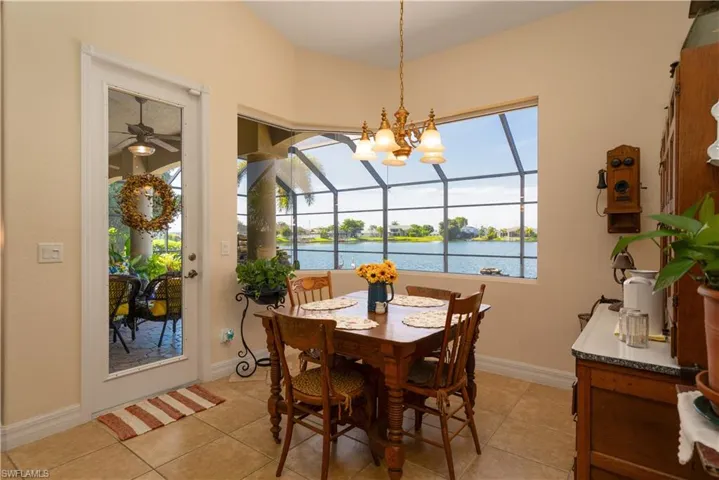 Tiled dining space with ceiling fan with notable chandelier, a water view, and a wealth of natural light