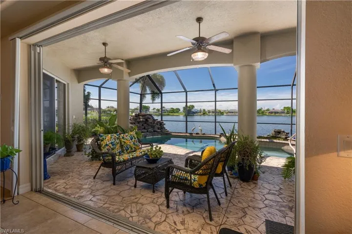 View of patio featuring a water view, ceiling fan, and a lanai