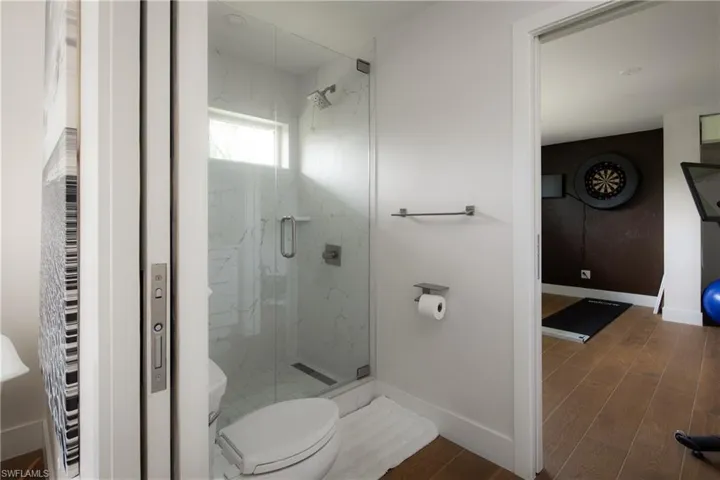 Bathroom featuring toilet, an enclosed shower, and hardwood / wood-style floors