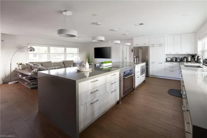 Kitchen featuring white cabinetry, high end refrigerator, sink, dark wood-type flooring, and a spacious island