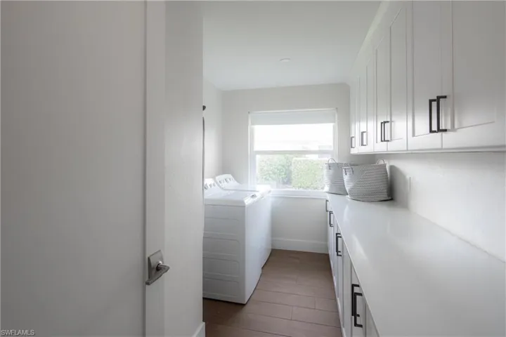Washroom with separate washer and dryer, cabinets, and dark hardwood / wood-style floors