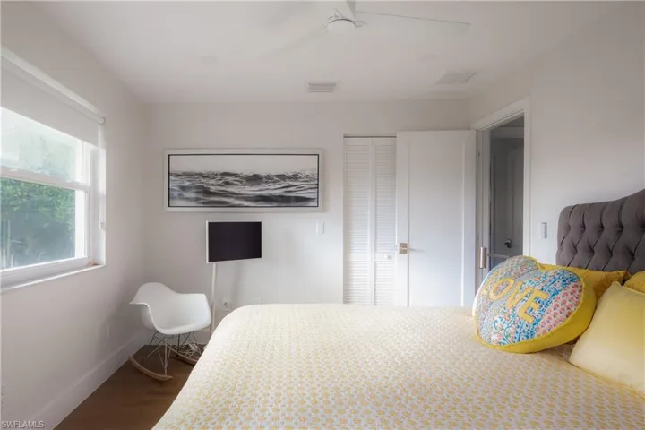 Bedroom with dark hardwood / wood-style flooring, ceiling fan, and a closet